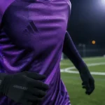 Maillot de foot violet sur joueur en course, terrain synthétique